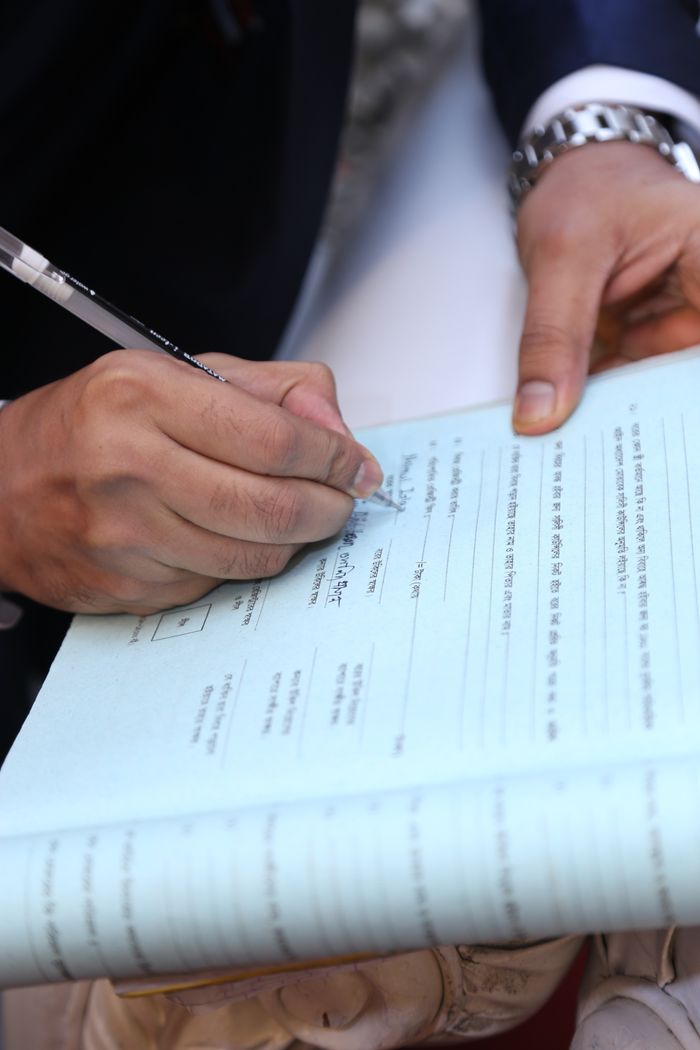 Home Close-up of hands filling out a document on a clipboard, demonstrating formal handwriting.