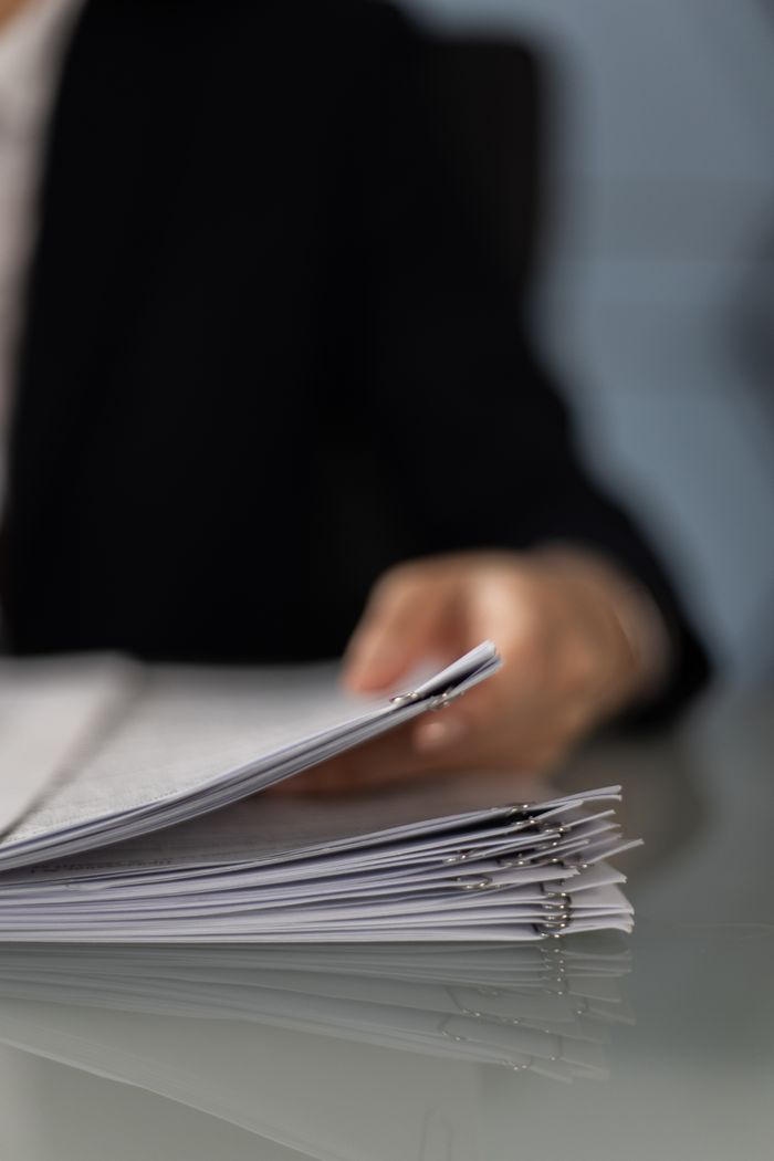 The Art of Drawing Readers In: Your attractive post title goes here Blurred hand holding a stack of documents on a glass desk with focus on papers.