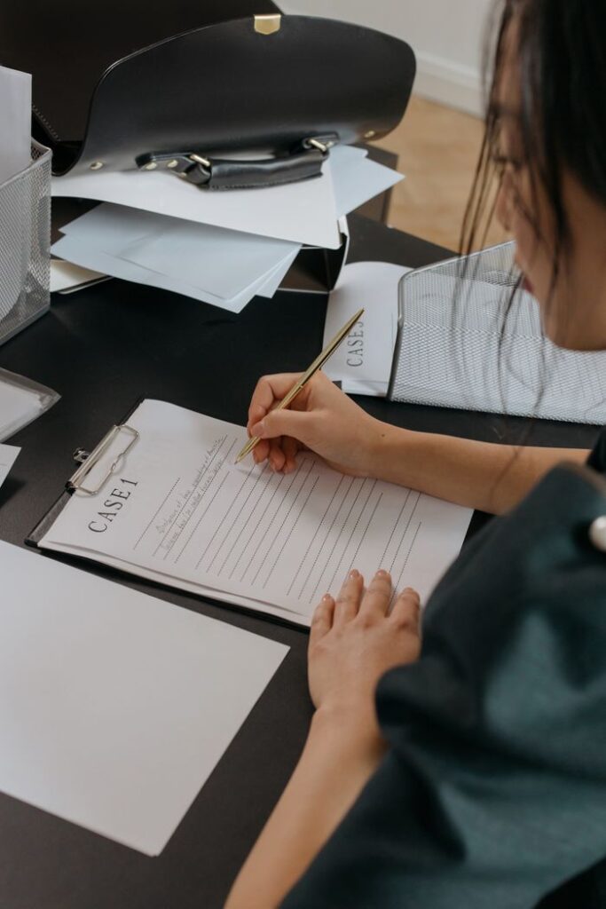 Hello world! A woman focused on reviewing paperwork at an office desk, capturing a professional working environment.