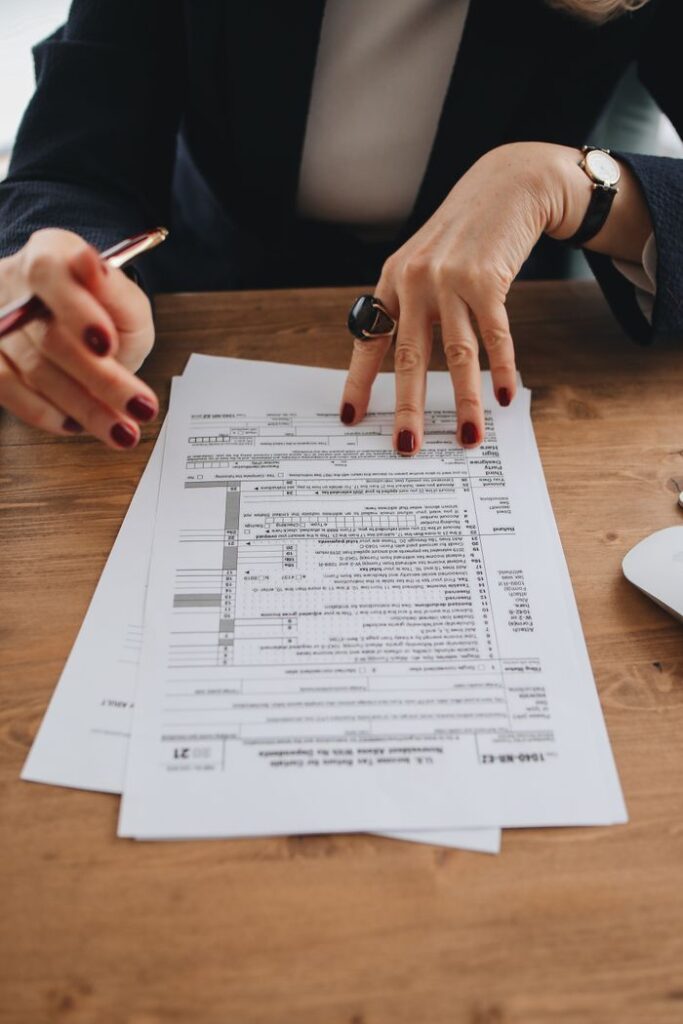 Mastering the First Impression: Your intriguing post title goes here Hands with manicured nails examining tax forms on wooden table indoors.
