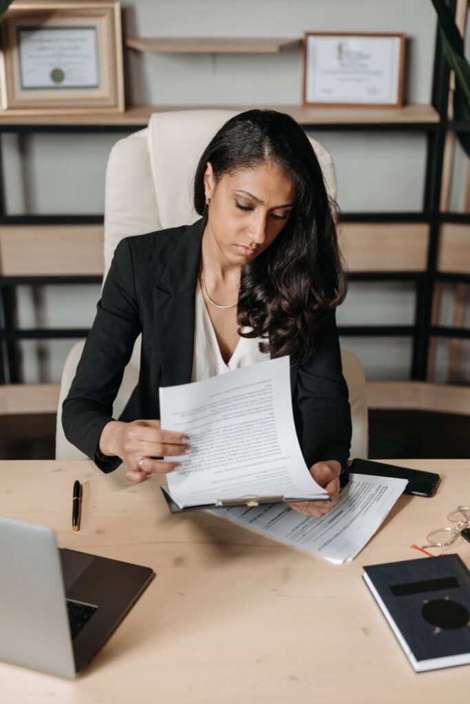 Crafting Captivating Headlines: Your awesome post title goes here A businesswoman in a blazer carefully reviews documents at her desk, symbolizing dedication and diligence.