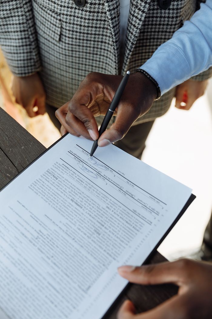 Наши услуги Detailed view of a person signing a business contract with a pen, emphasizing agreement and ownership.