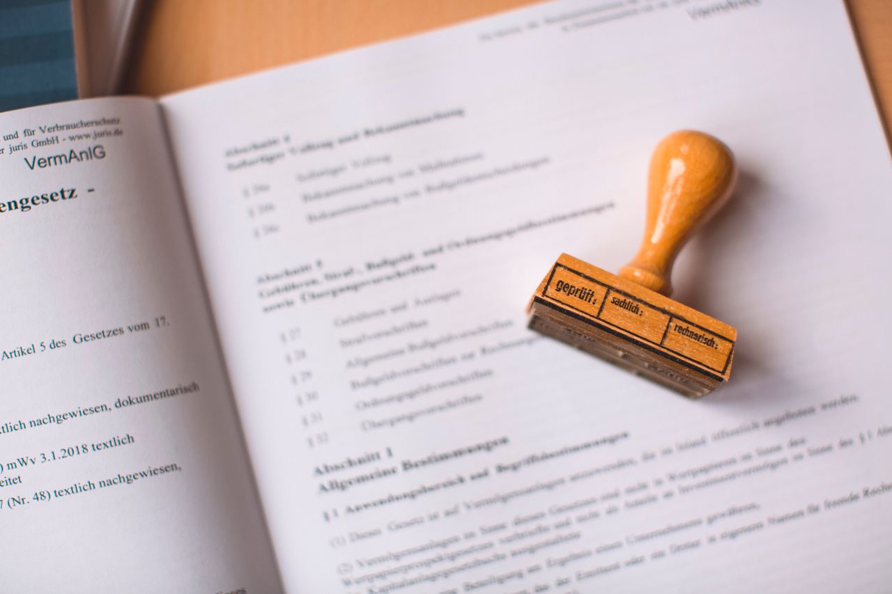 Наши услуги Close-up of a legal document with a wooden stamp placed on top, highlighting verification.